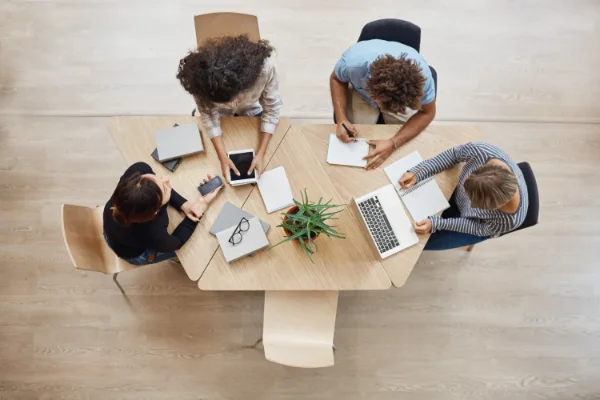 Vue du dessus d'une équipe de quatre collaborateurs qui travaillent autour d'une table
