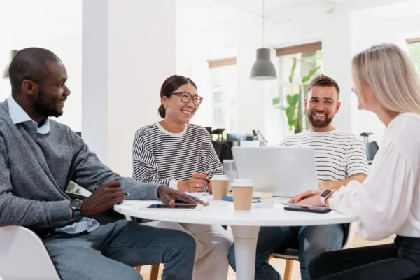 Réunion d'équipe détendue autour d'une table, avec des collaborateurs souriants