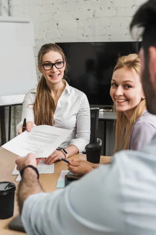Entretien de recrutement : un document est remis à deux candidates lors d'un rendez-vous